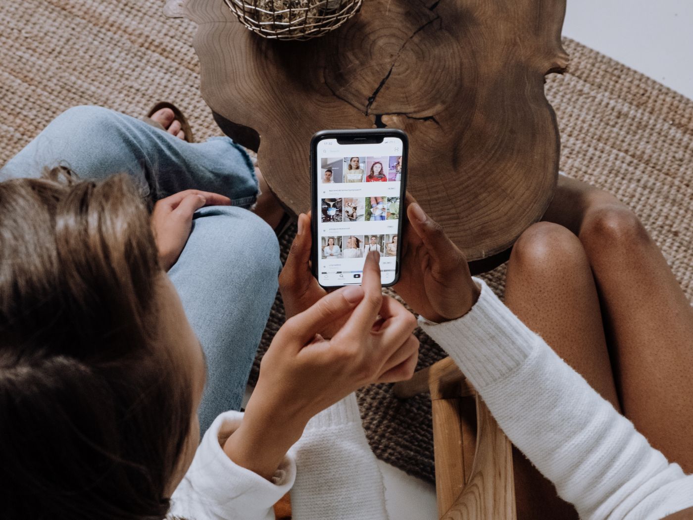 Two women scrolling through social media together on a smart phone