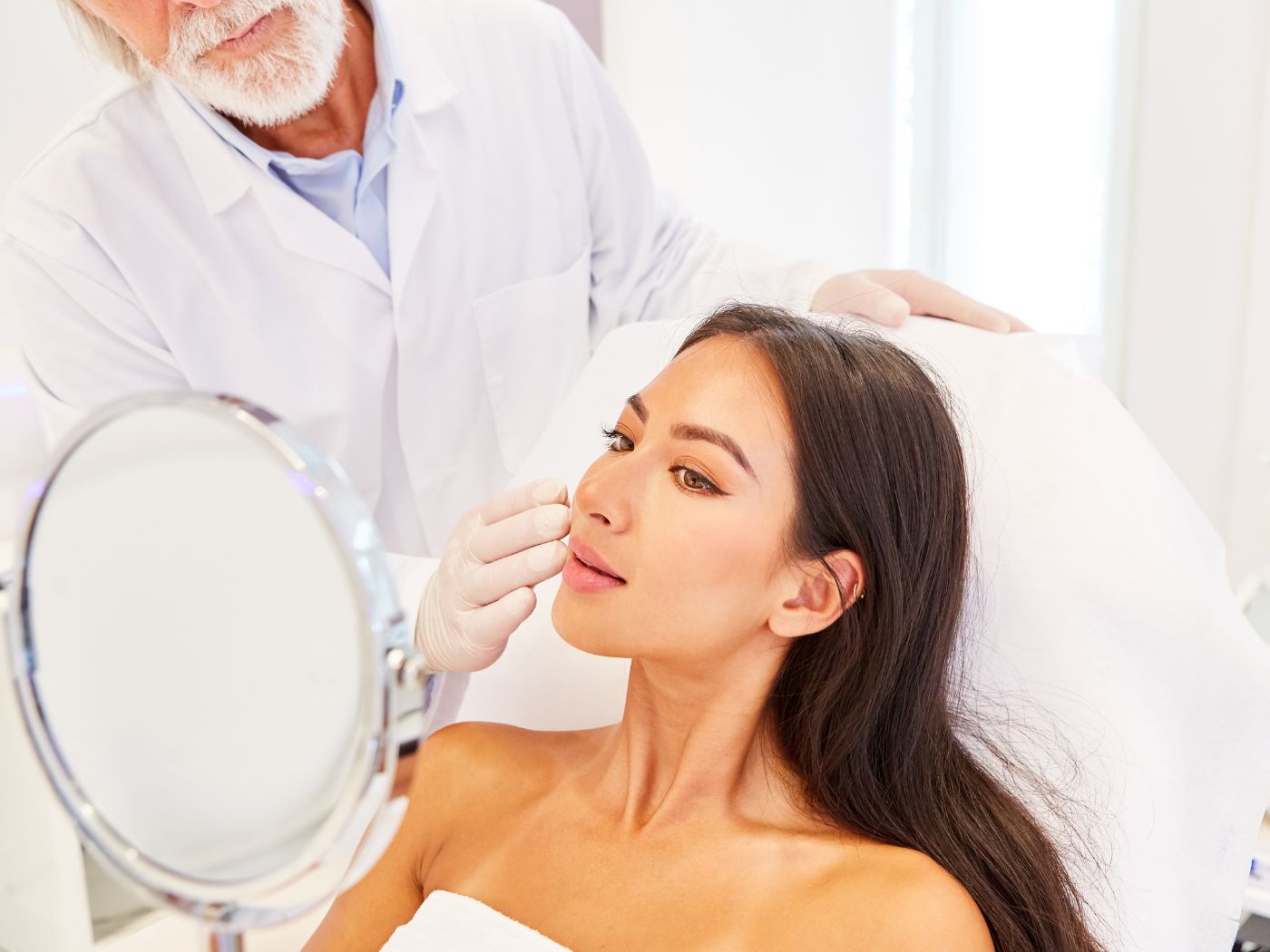 Dermatologist working with a patient as she looks in the mirror