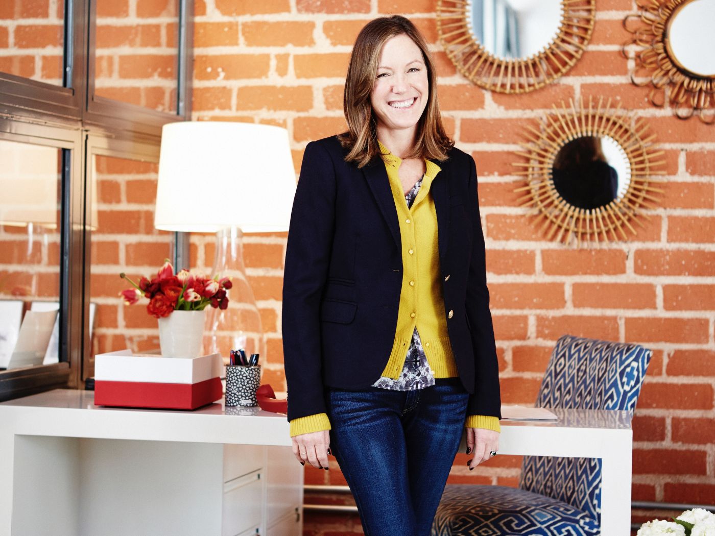 Gregg Standing In Front Of A Desk And Brick Wall With Decorative Mirrors