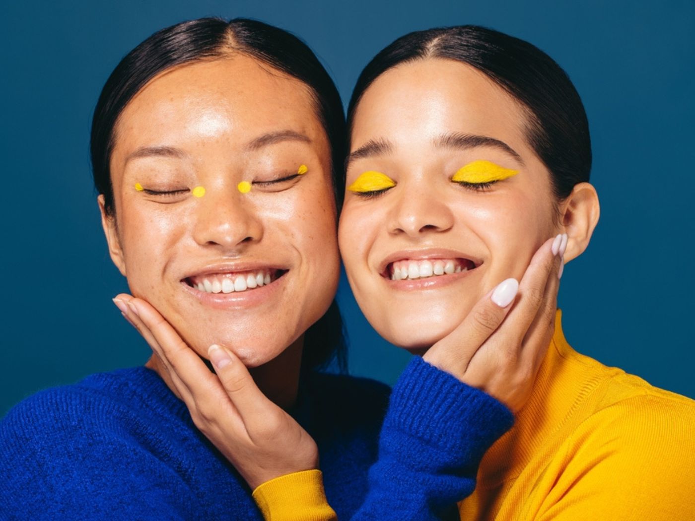 Two women hugging cheek to cheek with happy smiles and eyes closed