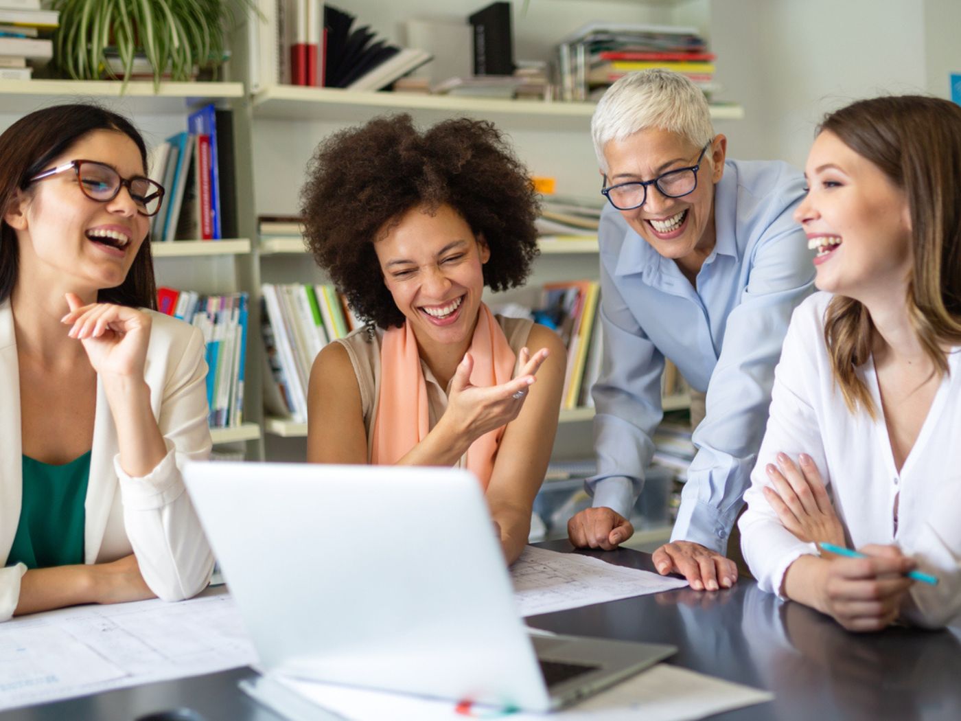 Four women of varying ages working together around a laptop