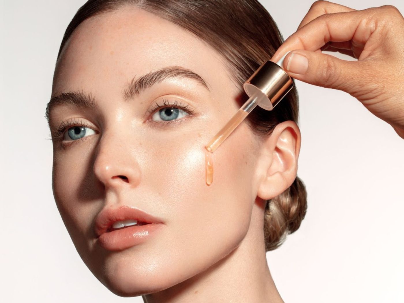 Woman with a tincture of product being applied to her cheek