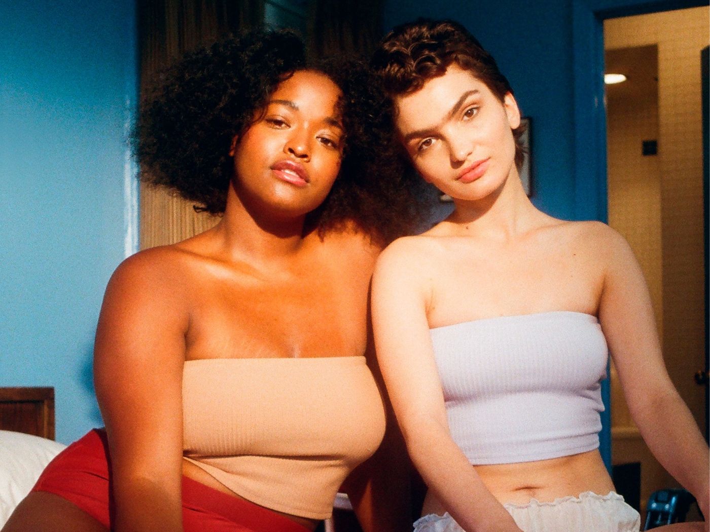 Two gen Z women sitting together in neutral tubetops